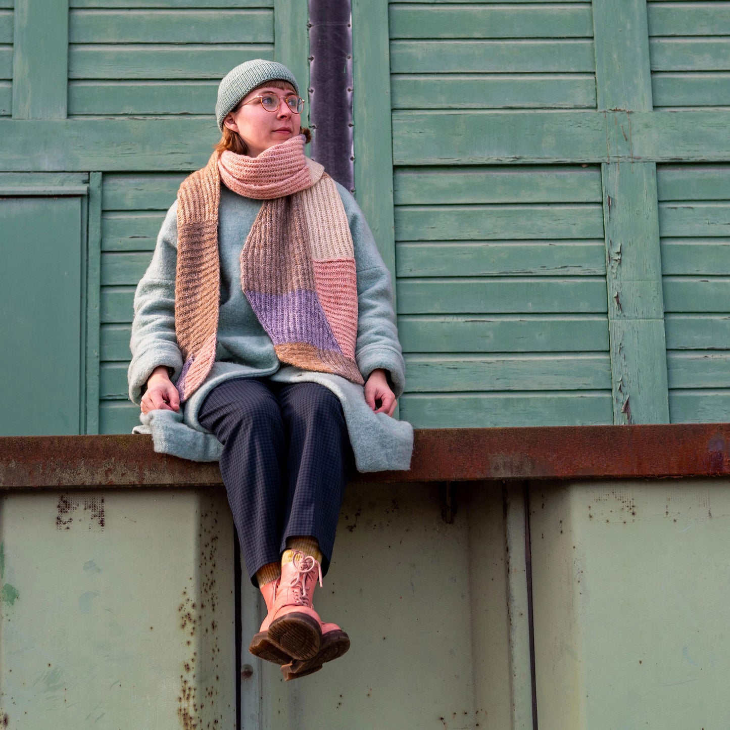 Anna Husemann sitting in a green harbour spot wearing her Forming Scarf.