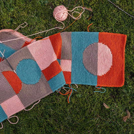 Intarsia Tiles Scarf in progress laying on the grass.