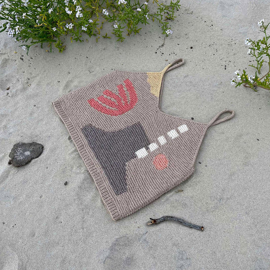 Intarsia Top knitting pattern laying on the beach.