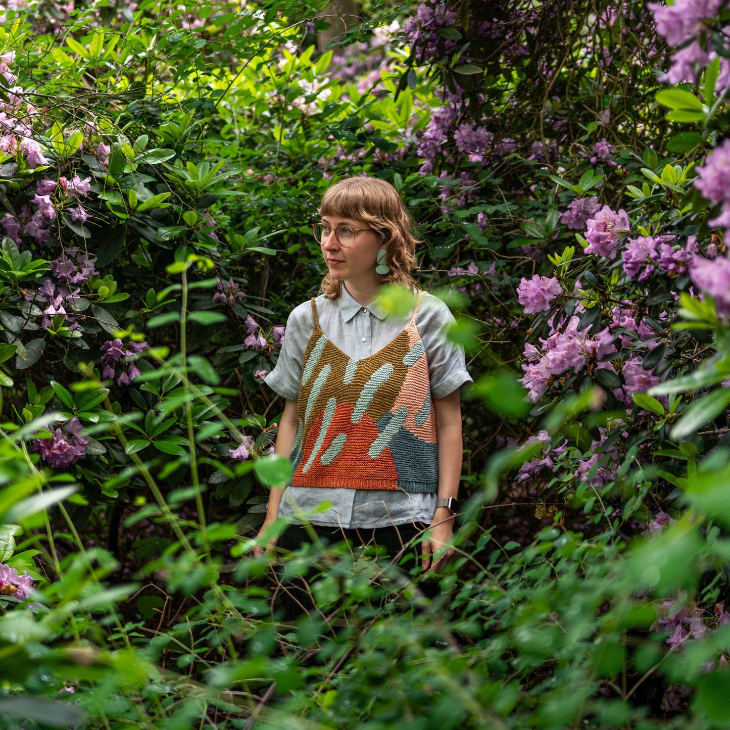 Anna Husemann wearing her Intarsia Top surrounded by leaves and flowers.