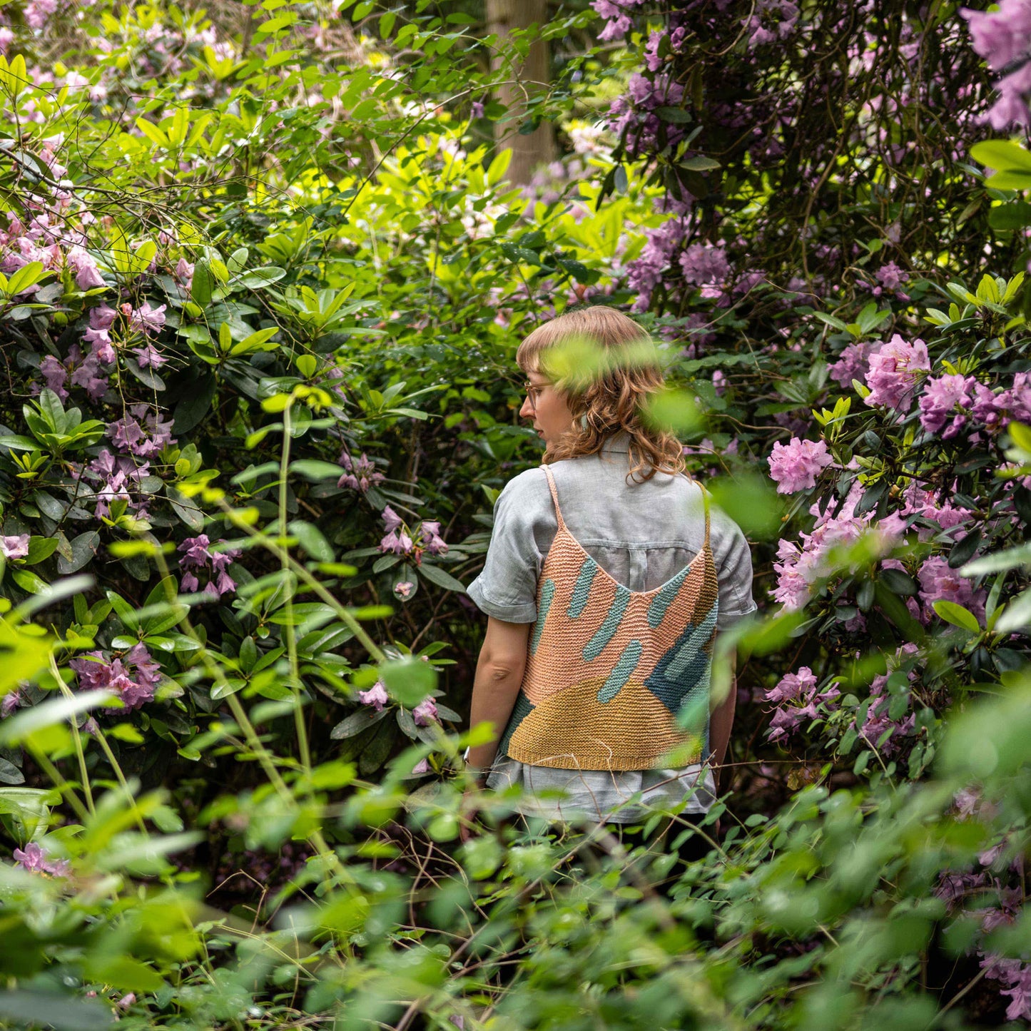 Anna Husemann wearing her Intarsia Top surrounded by leaves and flowers.