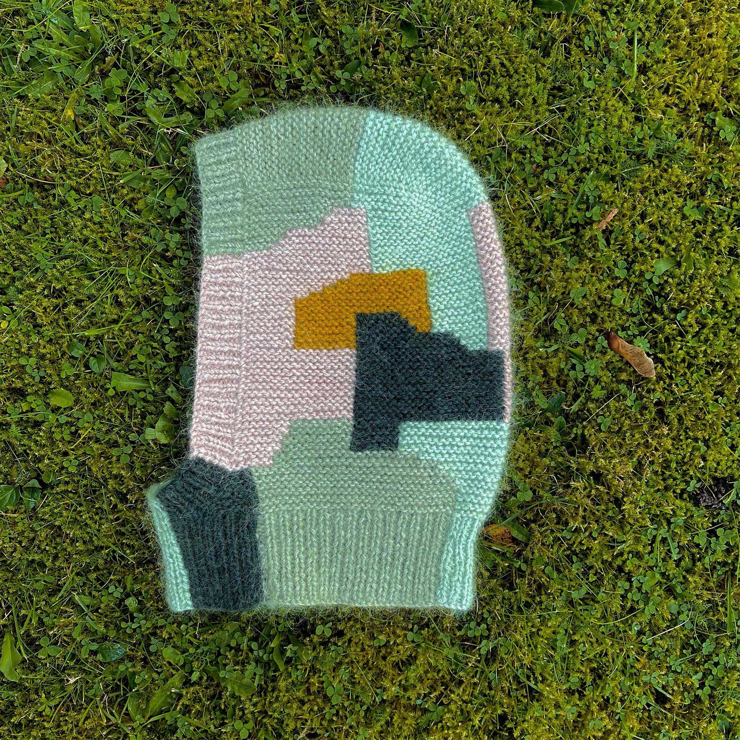 Intarsia Balaclava knitting pattern laying in the grass.