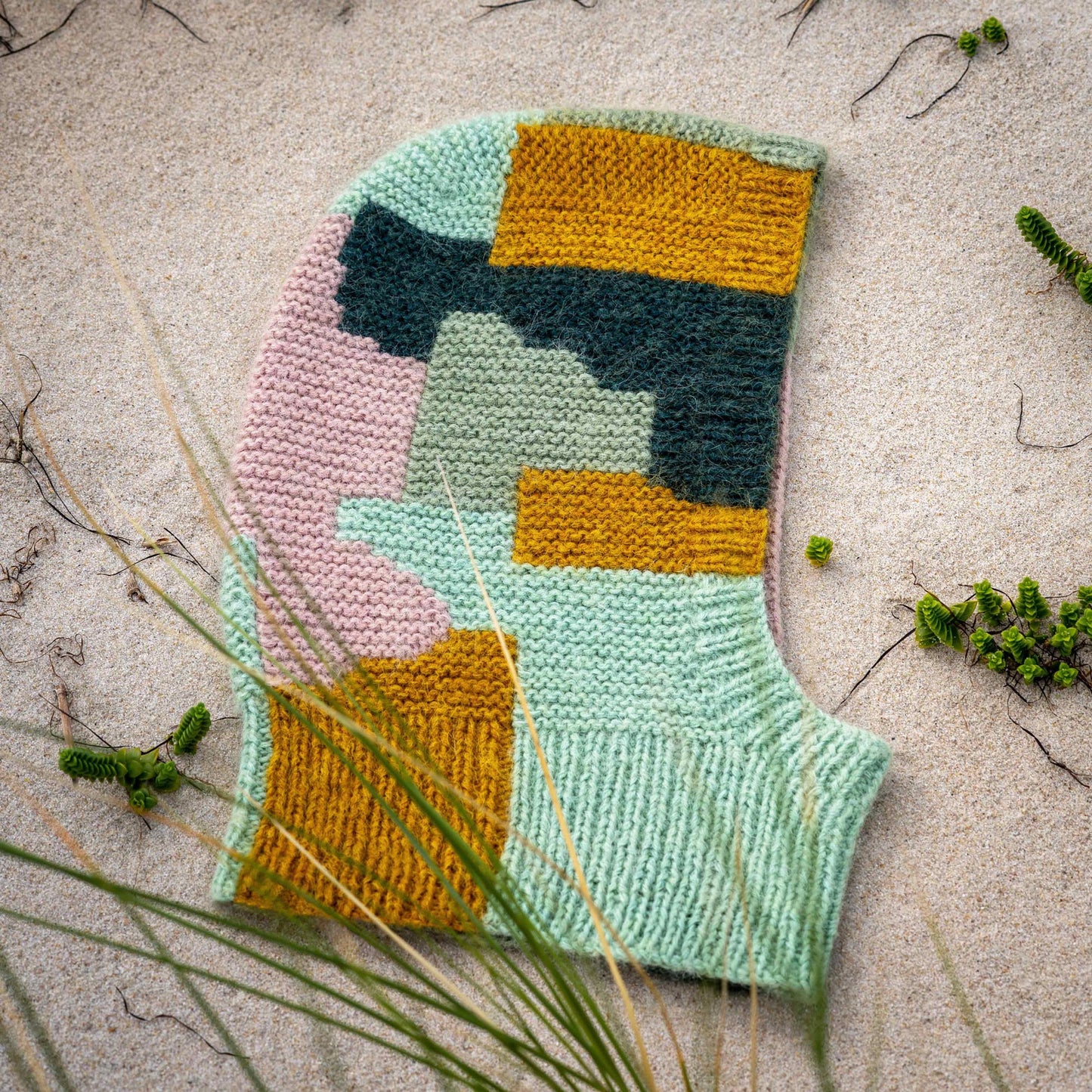 Intarsia Balaclava knitting pattern laying at the beach.